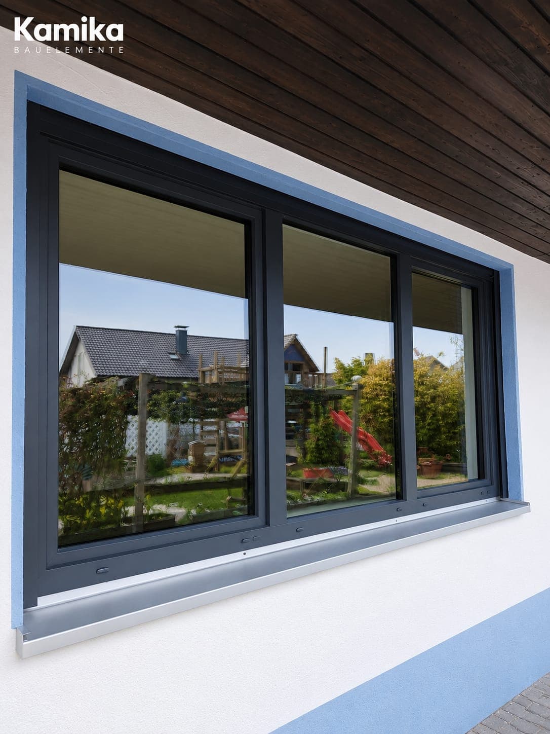Dreiteiliges Anthrazit-Fenster mit Aluminium-Fensterbank unter einem Holzdachüberstand